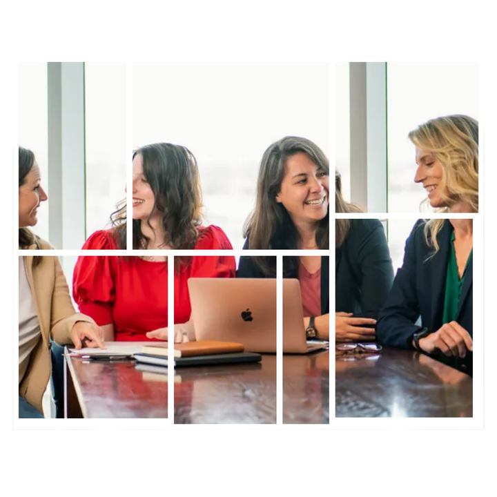 A group of women are sitting at a table with a laptop.