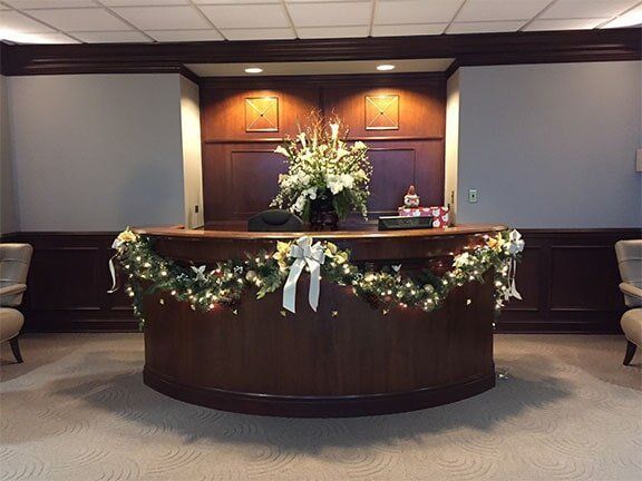 Decorated reception desk with white flowers and holiday garland in a lobby