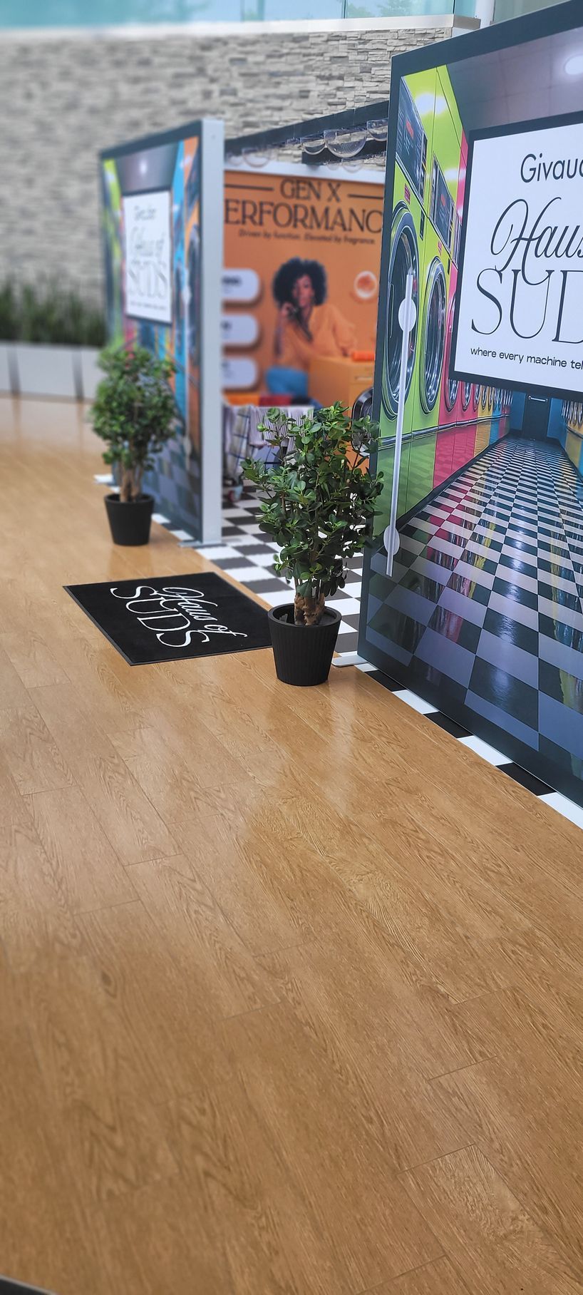 Row of tabletop display signs and small potted plants on a wooden surface at an event.