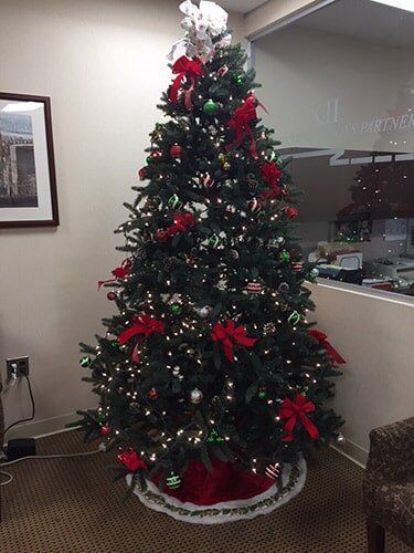 Decorated Christmas tree with red ribbons and ornaments in an office corner