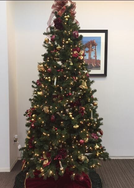 Decorated Christmas tree with lights and ornaments in a room near a framed picture