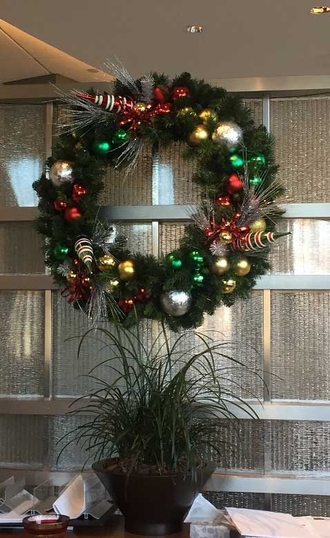 Decorated Christmas wreath on a wall above a potted plant and table setting