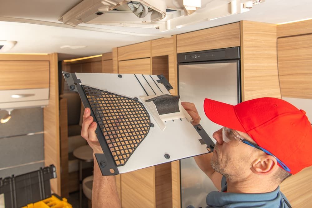 A Professional RV Appliances Specialist In A Red Hat Holding A Vent — Trusted Mechanic in Hervey Bay