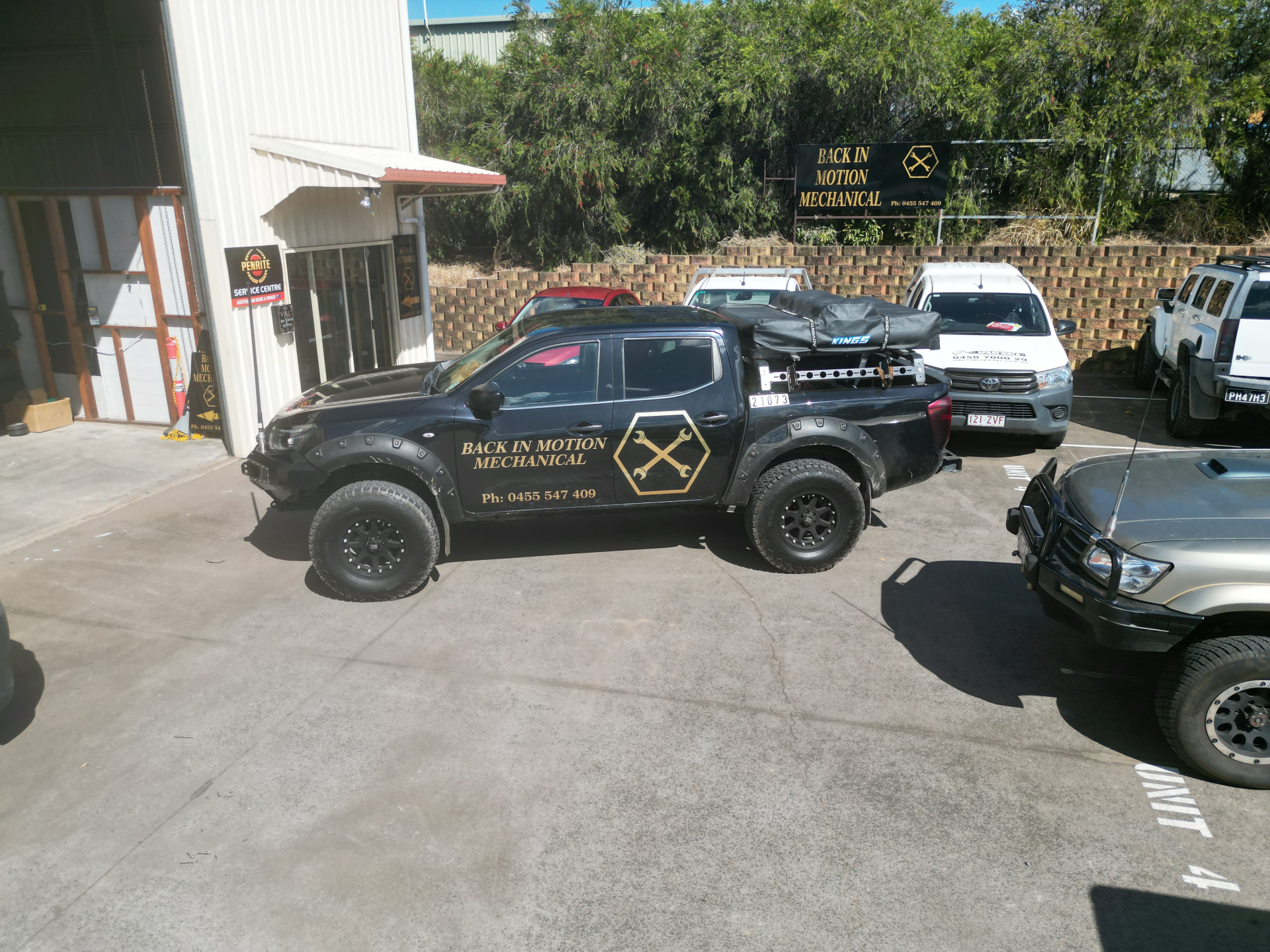 A row of trucks are parked in a parking lot in front of a building.