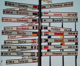 Signpost with directions and distances to various international cities.