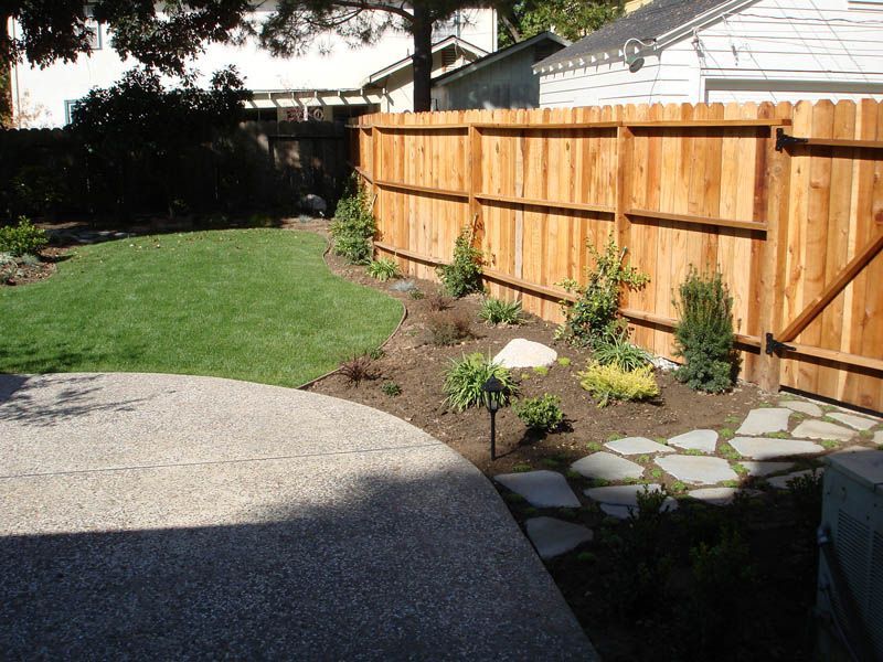 A wooden fence surrounds a lush green yard
