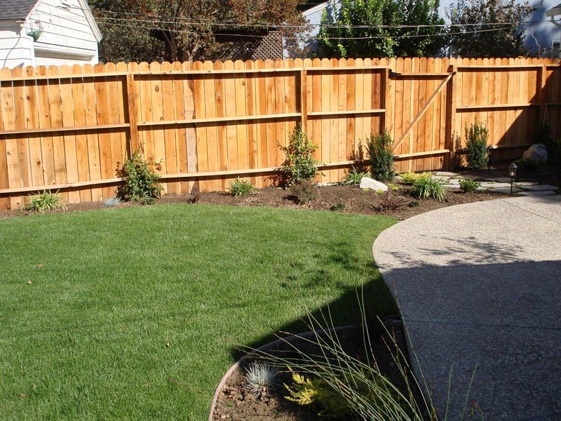 A wooden fence surrounds a lush green lawn
