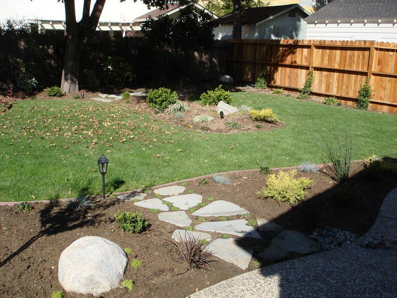 A backyard with a wooden fence and a stone walkway
