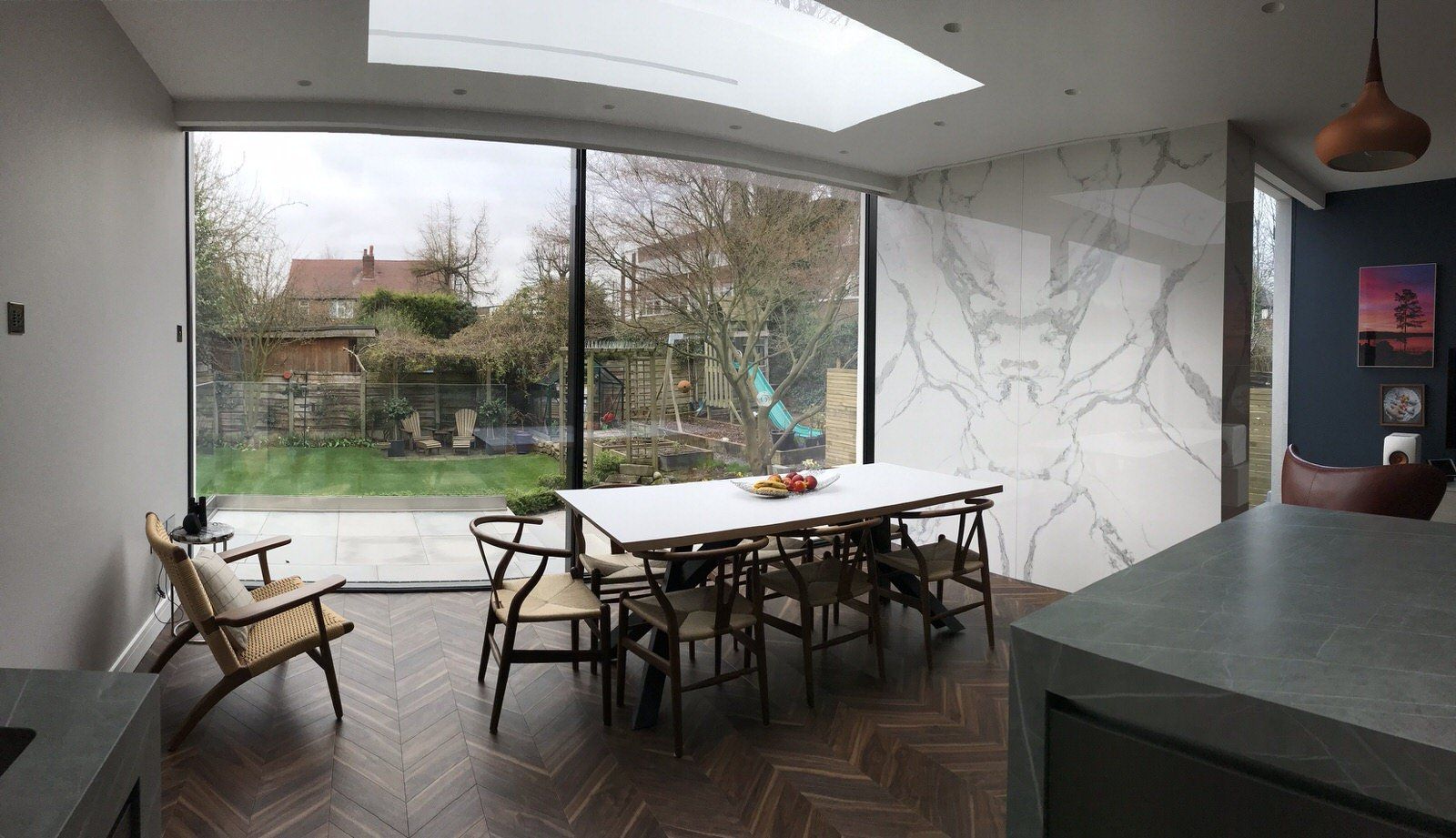 High-performance frameless glass doors, windows, and a skylight in bright kitchen extension