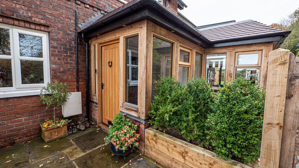 Front exterior of home showing single-storey oak-frame extension by Rawlinson Construction with York stone-paved driveway