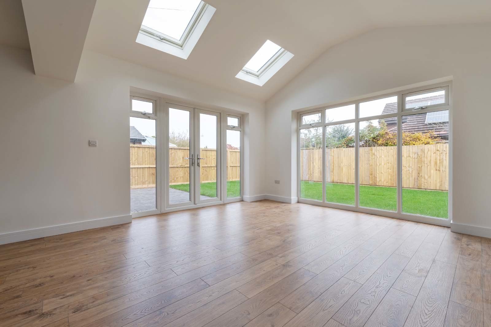 Bright living area with large windows and natural light in dormer bungalow by Rawlinson Construction