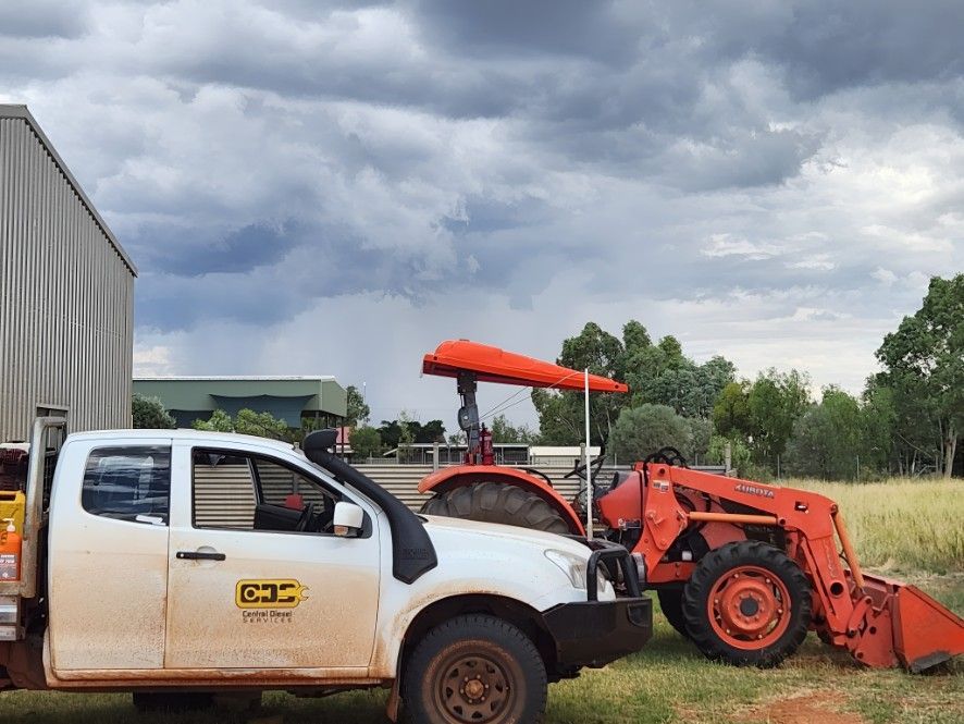 A White Truck Is Parked Next To A Large Orange Tractor — Central Diesel Services In Alice Springs, NT