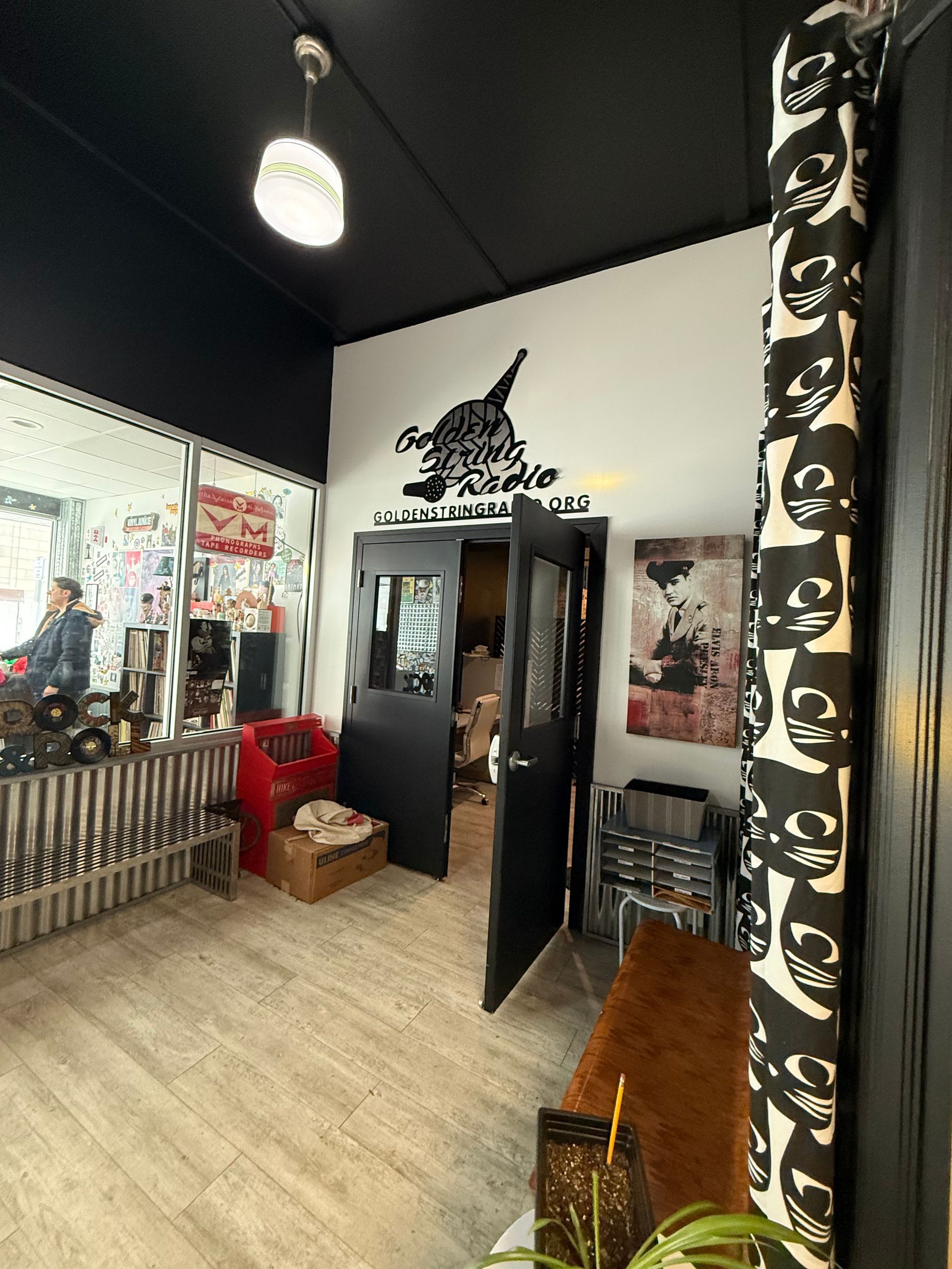 Interior shot of a shop entrance with black and white decor. Open door reveals another room.