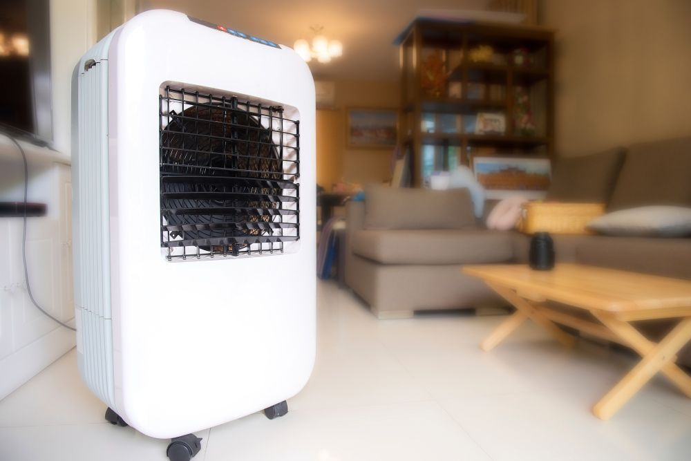 A White Air Cooler is Sitting in a Living Room Next to a Coffee Table — Unger Air in South Tamworth, NSW