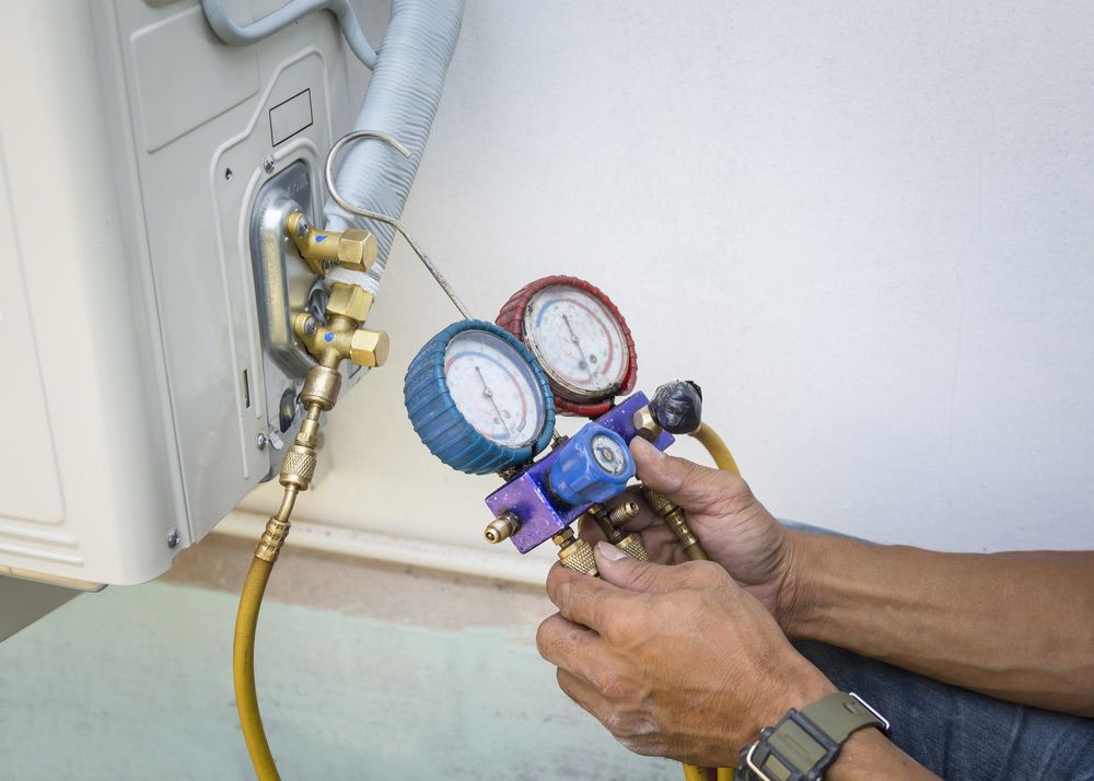 A Man is Working on an Air Conditioner With a Gauge Attached to It — Unger Air in South Tamworth, NSW