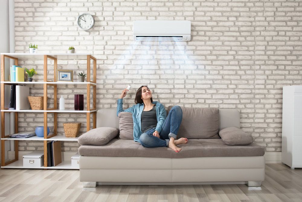 A Woman is Sitting on a Couch in a Living Room Under an Air Conditioner — Unger Air in South Tamworth, NSW