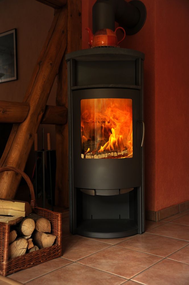 A Black Wood-burning Stove With a Lit Fire Stands — Unger Air in Armidale, NSW