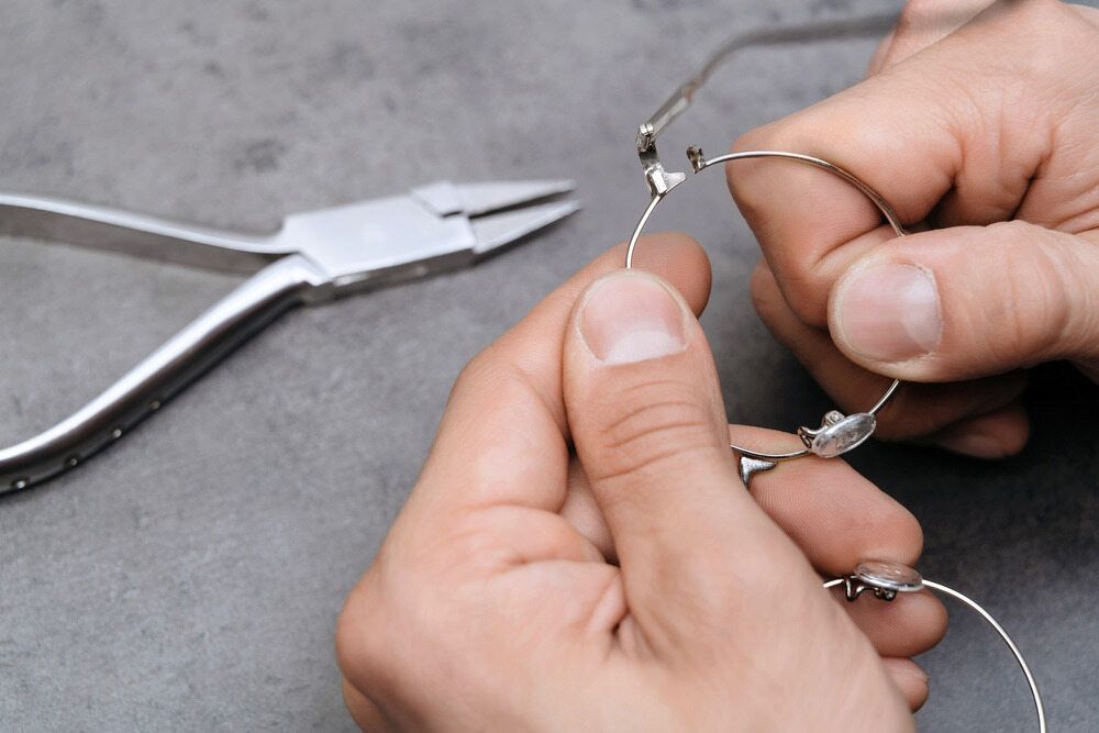 A Person Is Fixing A Pair Of Glasses With Pliers — Eye Supply In Mareeba, QLD