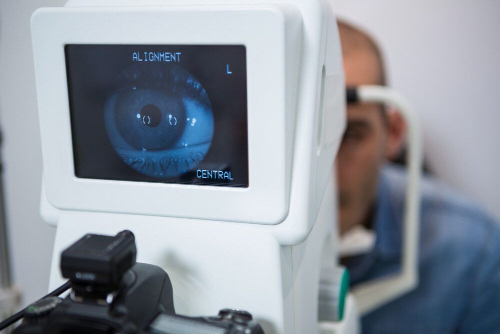 A Man Is Getting His Eyes Checked By An Ophthalmologist — Eye Supply In Mareeba, QLD