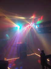Party lights illuminating a room, centered on a sound system, creating a colorful atmosphere.
