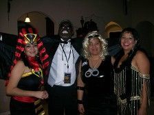Group of four people in costumes pose together at a party.