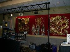 DJ setup with lights, a disco ball, and gold dragons against a red backdrop.