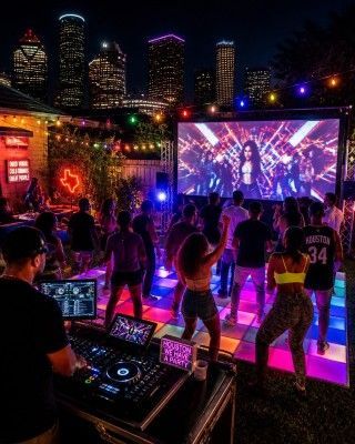 Elegant concert hall with colorful stage lights, LED backdrop, and seated audience at candlelit tables