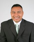 Man in black suit and green tie smiling at the camera.