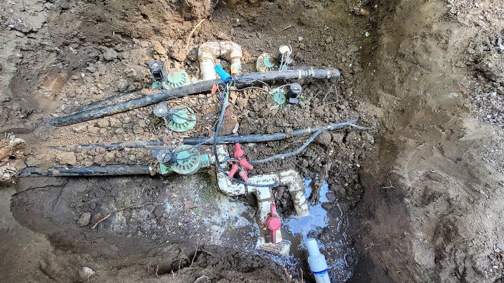 A bunch of pipes are laying in the dirt.