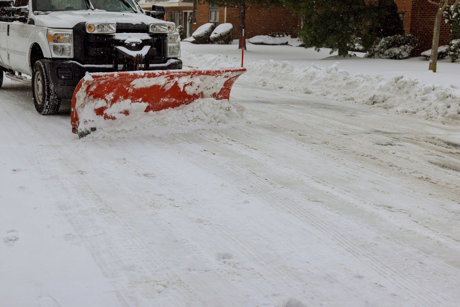 A snow plow is plowing snow on the side of the road.