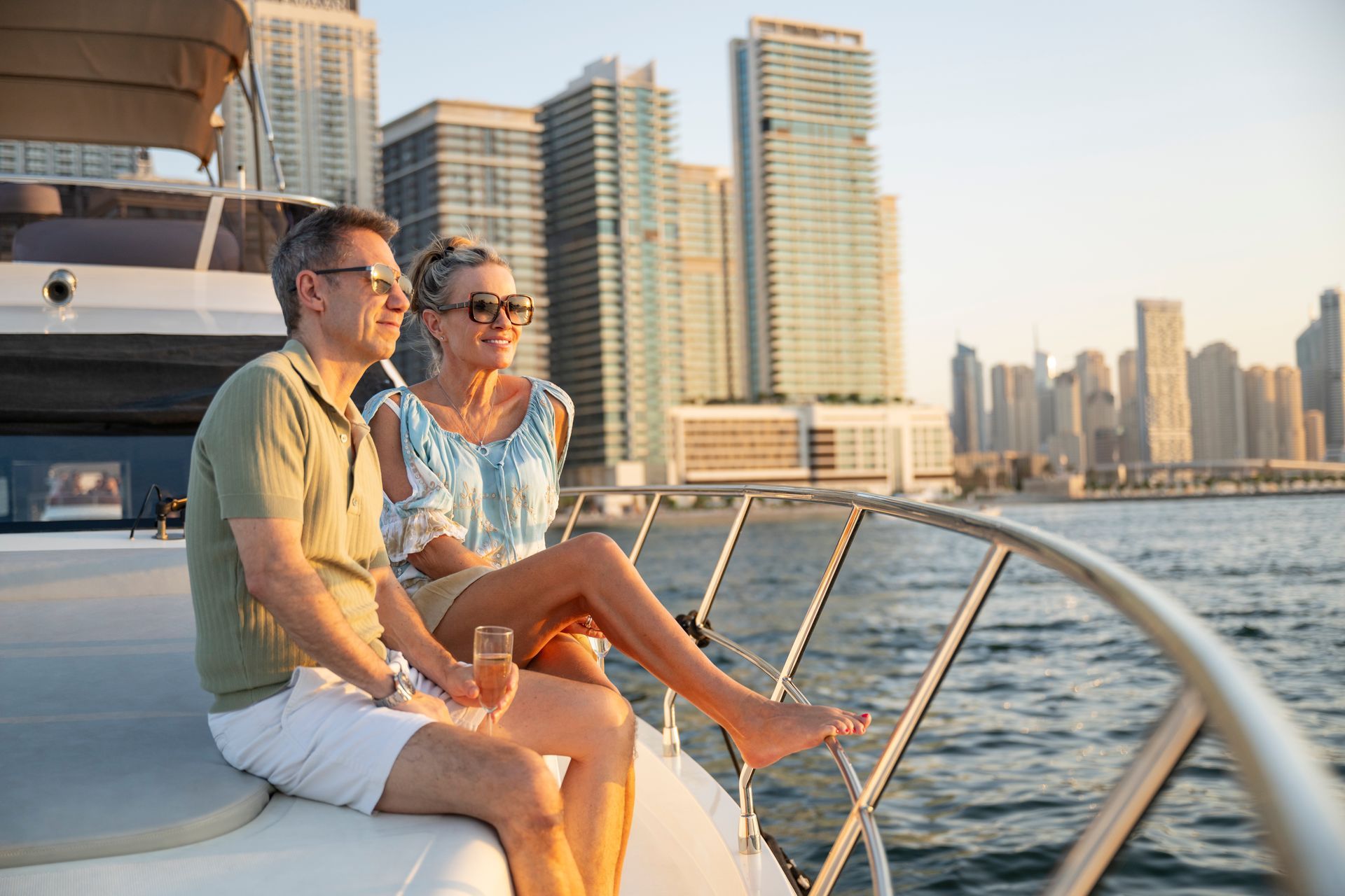 Couple on yacht enjoying sunset with city skyline view.