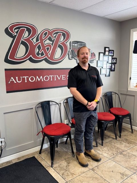 Group posing in front of B&B Automotive Services sign and vintage red car mural