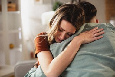 Deux personnes enlacées à l'intérieur, l'une d'elles les yeux fermés et l'air soulagée