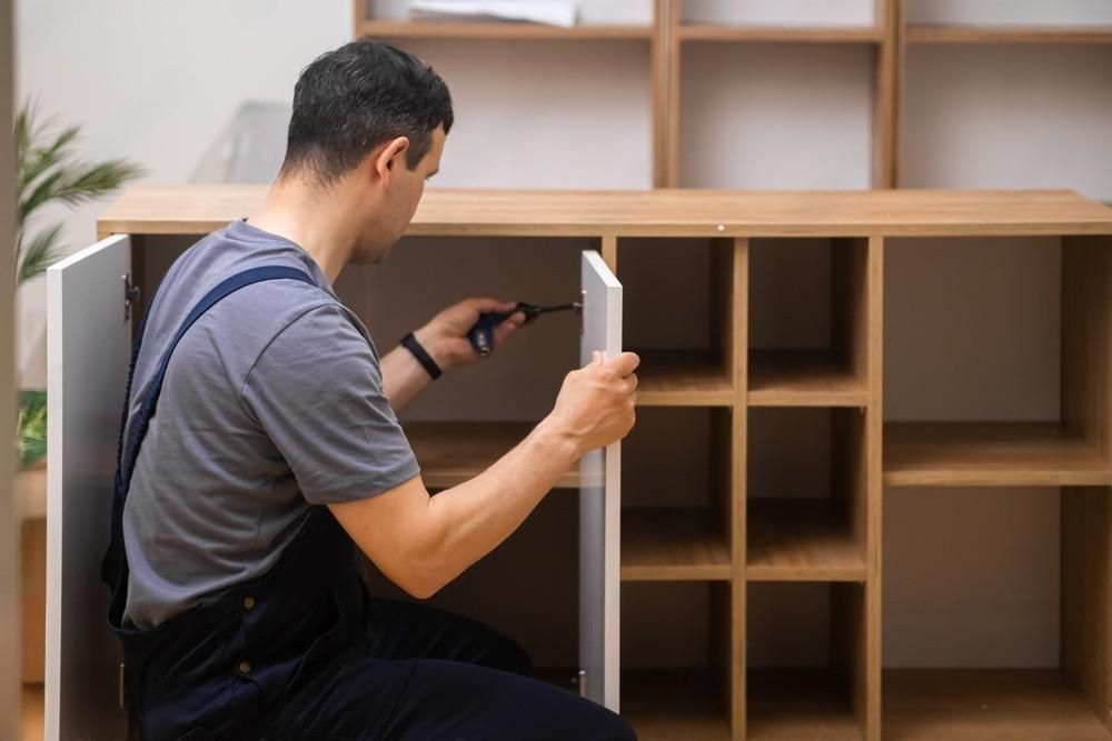 a man is fixing a cabinet with a screwdriver .