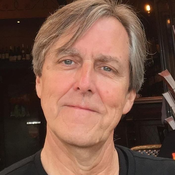A close up of a man 's face wearing a black shirt