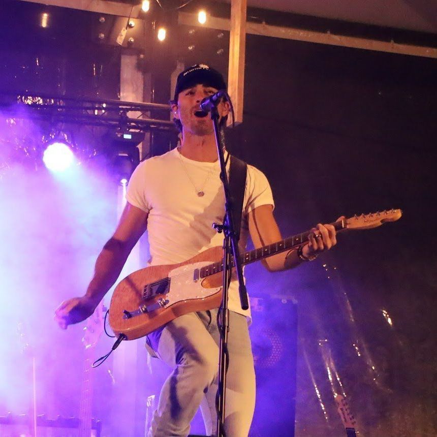 A man singing into a microphone while holding a guitar
