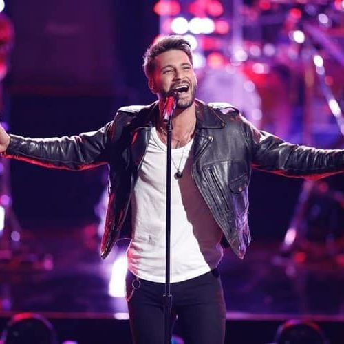 A man singing into a microphone with his arms outstretched