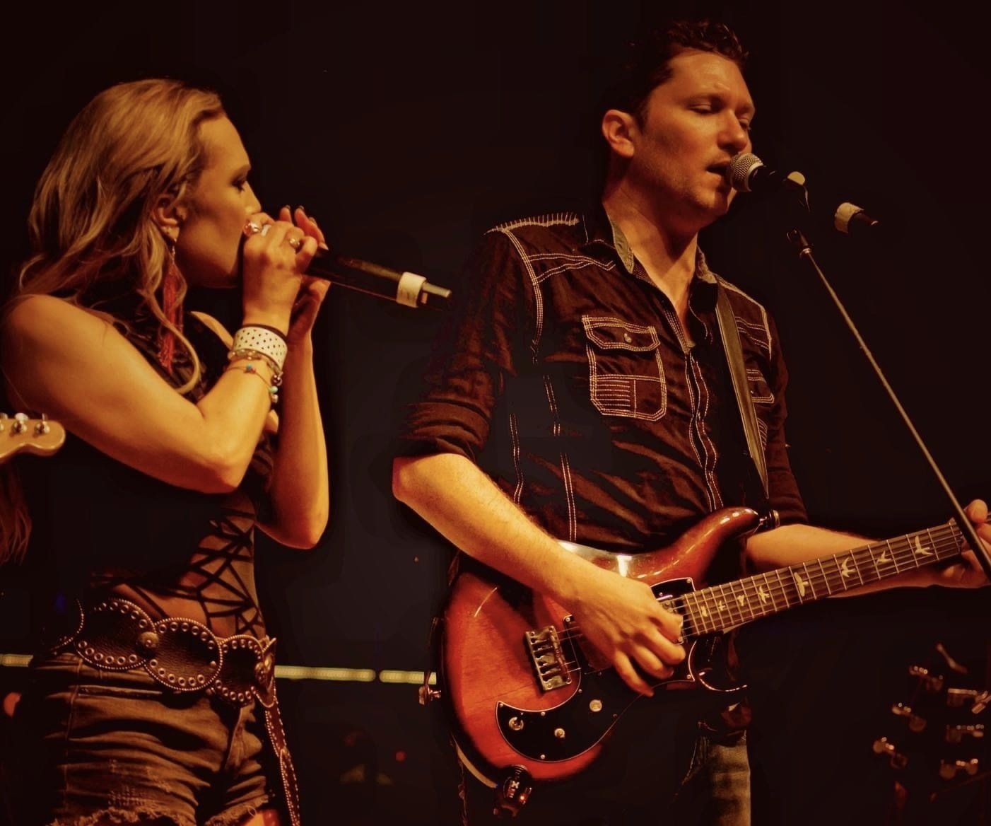 A man playing a guitar and a woman singing into a microphone