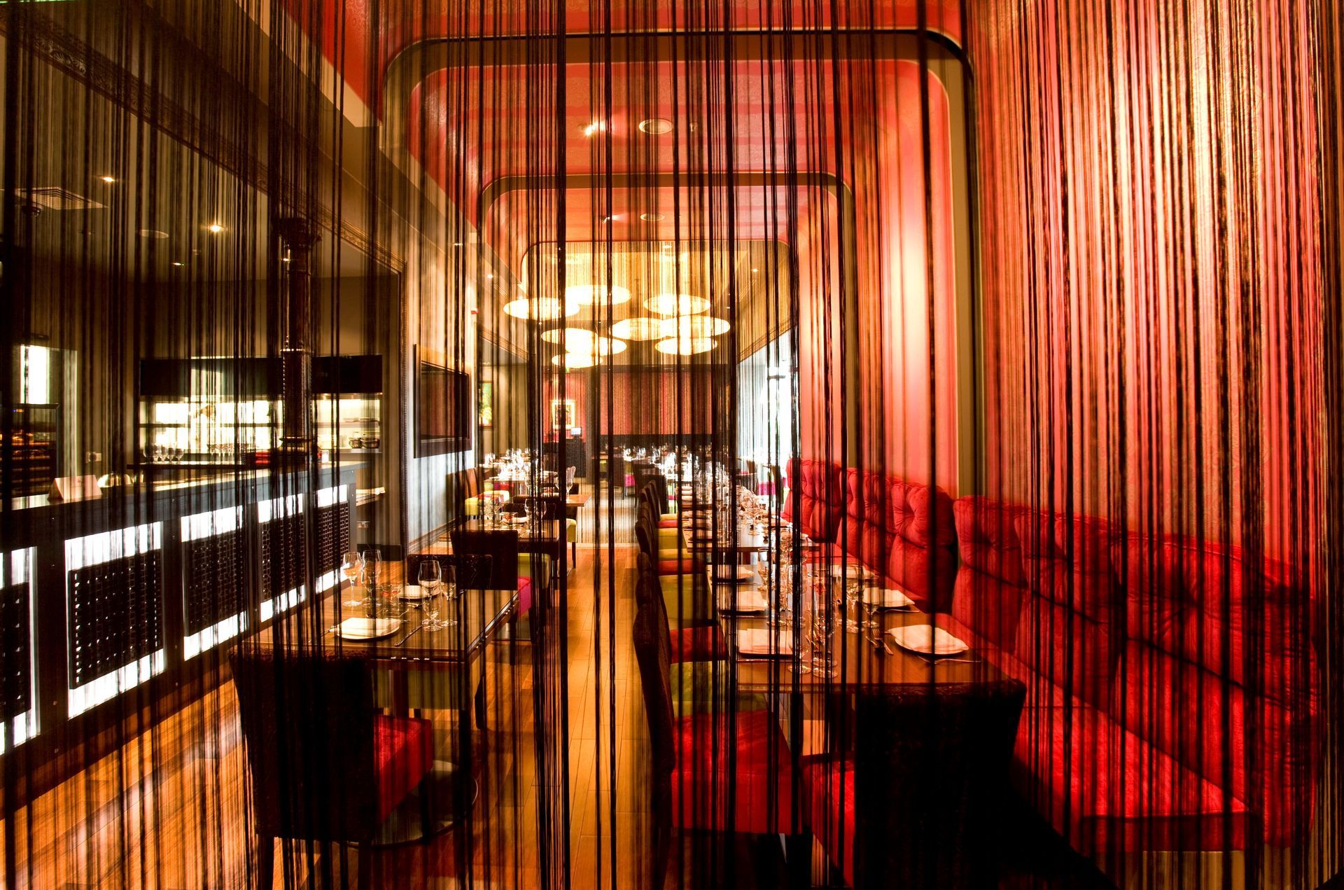 A restaurant with tables and chairs behind a red curtain