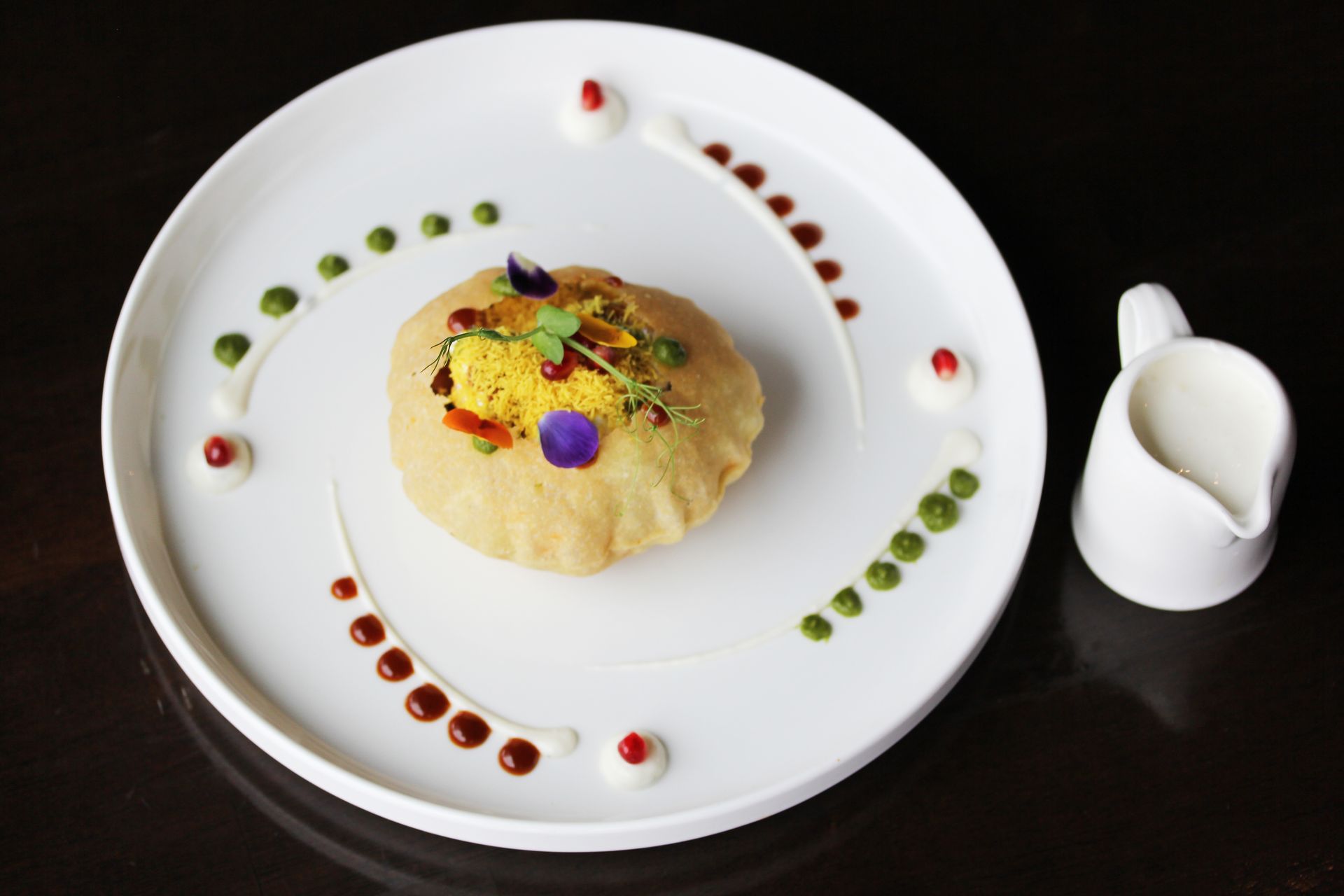 A white plate with a pastry on it next to a pitcher of milk