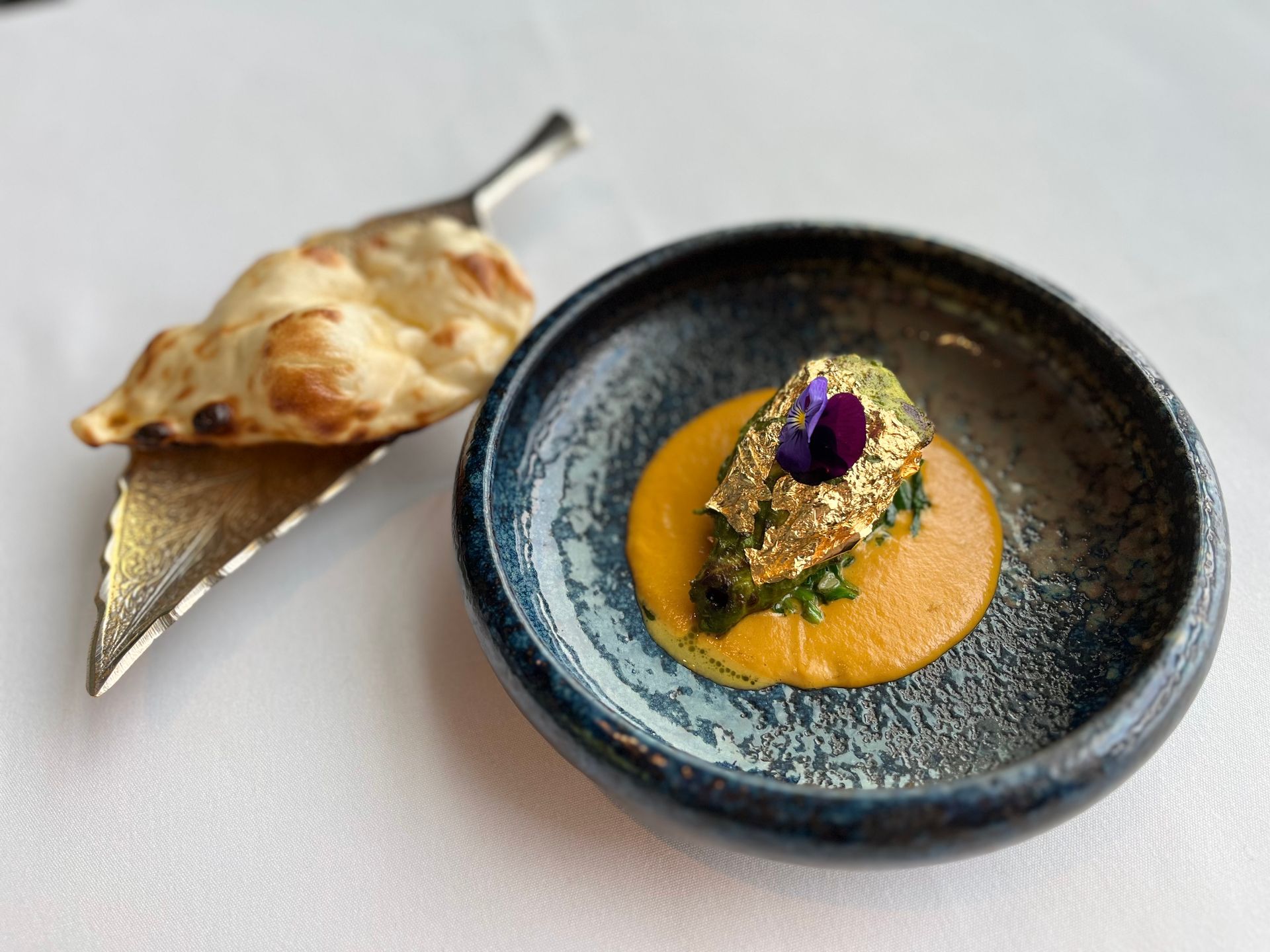 A close up of a plate of food next to a piece of bread on a table.