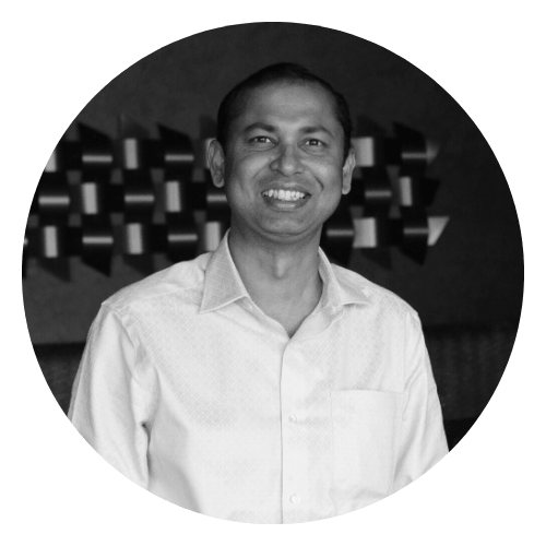A man in a white shirt is smiling in a black and white photo