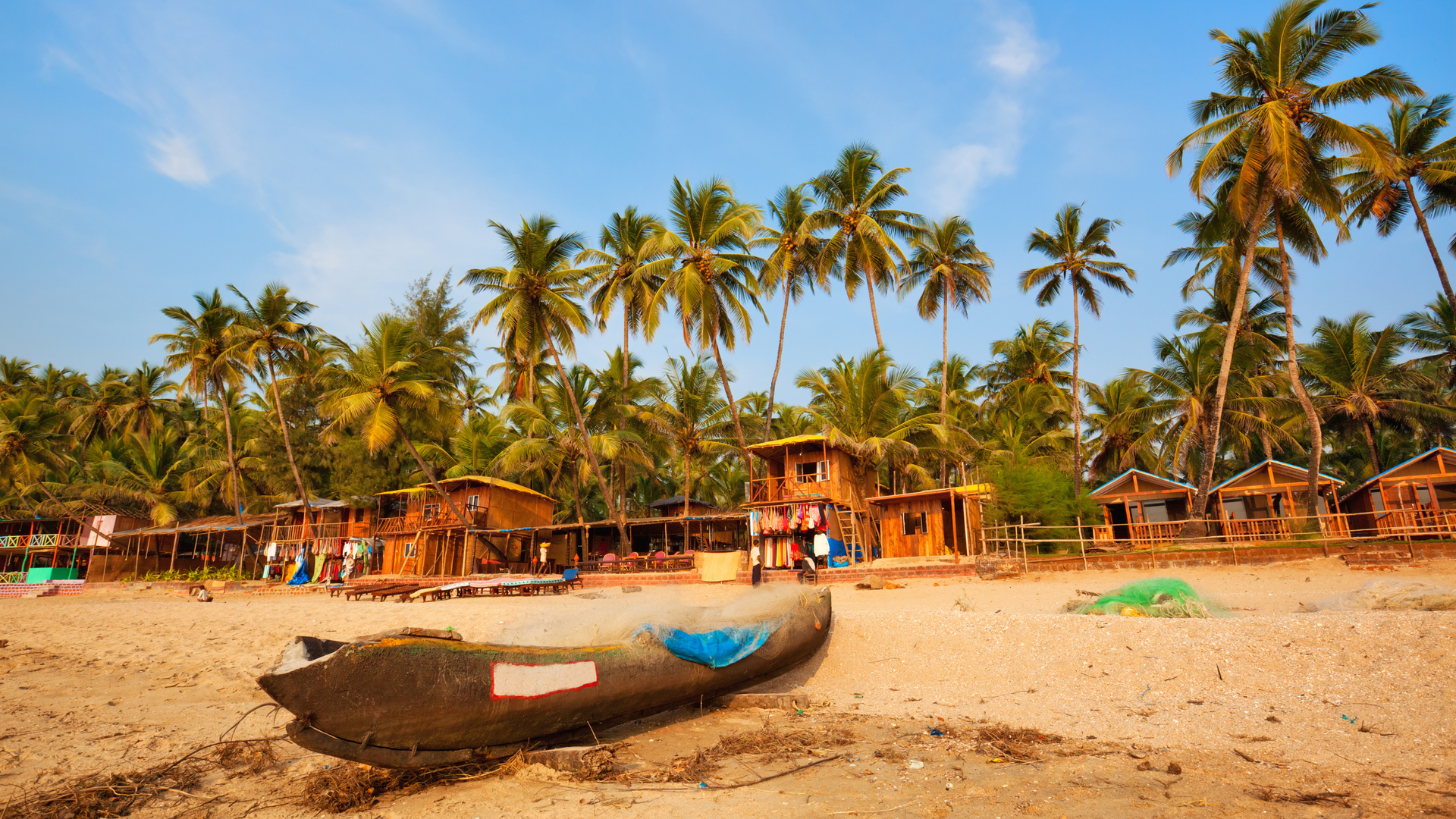 A boat is sitting on a sandy beach surrounded by palm trees.