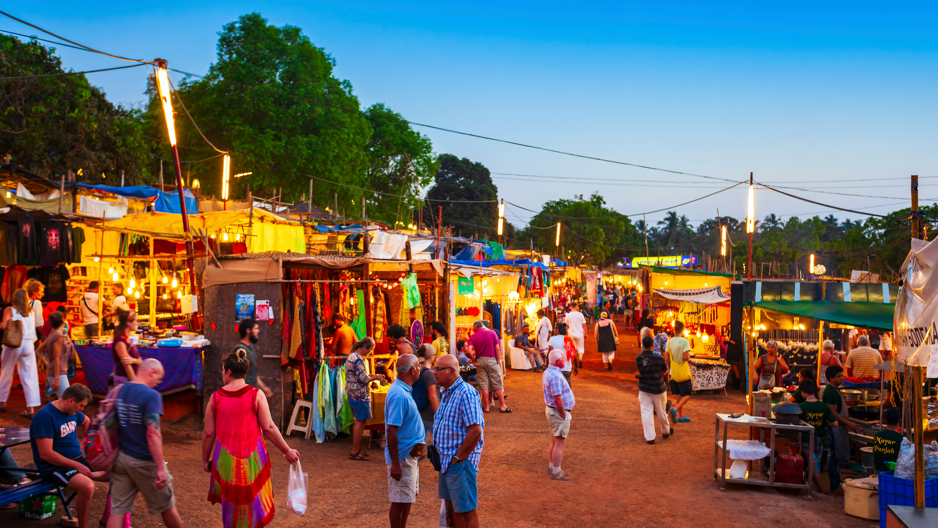 A crowd of people are walking through a market at night.