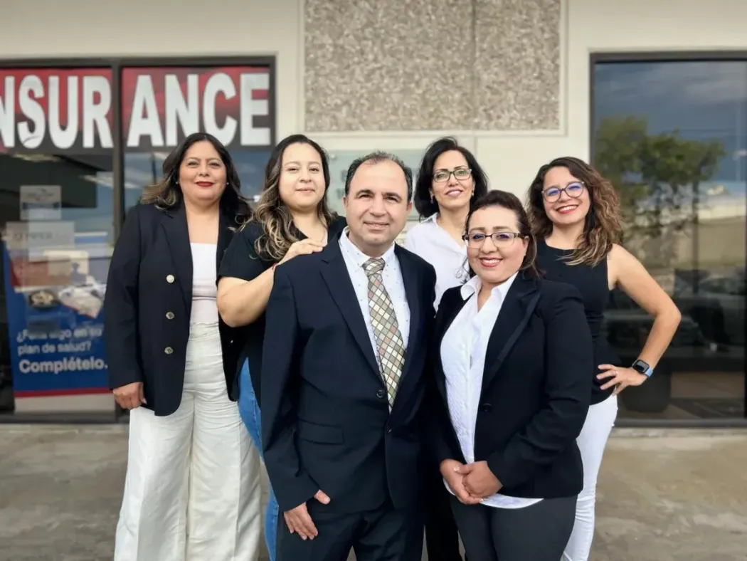 Group of six people posing outside an insurance office.