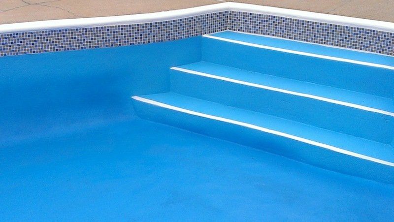 Une piscine bleue avec des escaliers qui y mènent.