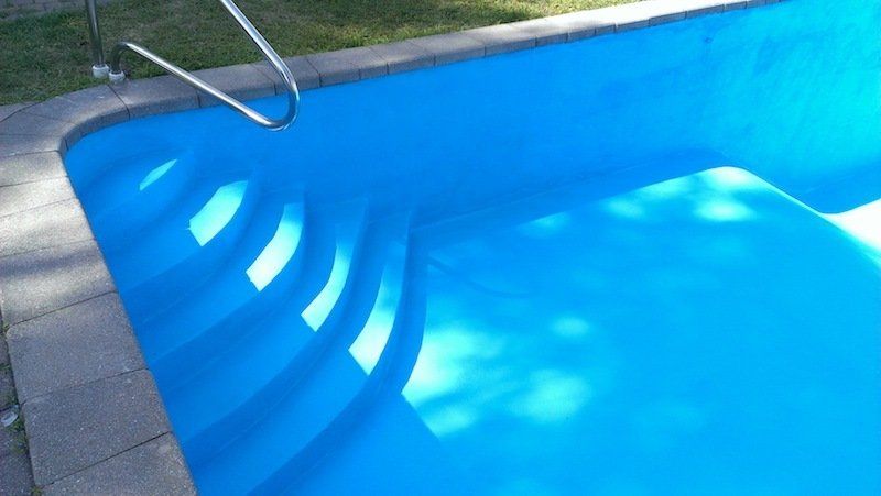 Une piscine bleue avec des escaliers qui y mènent