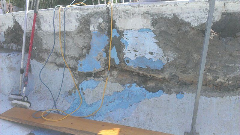 Un aspirateur est posé sur une planche de bois à côté d'un mur en béton.