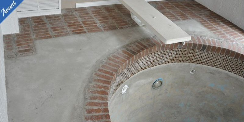 Un bain à remous est en cours de construction dans une pièce avec des briques au sol.