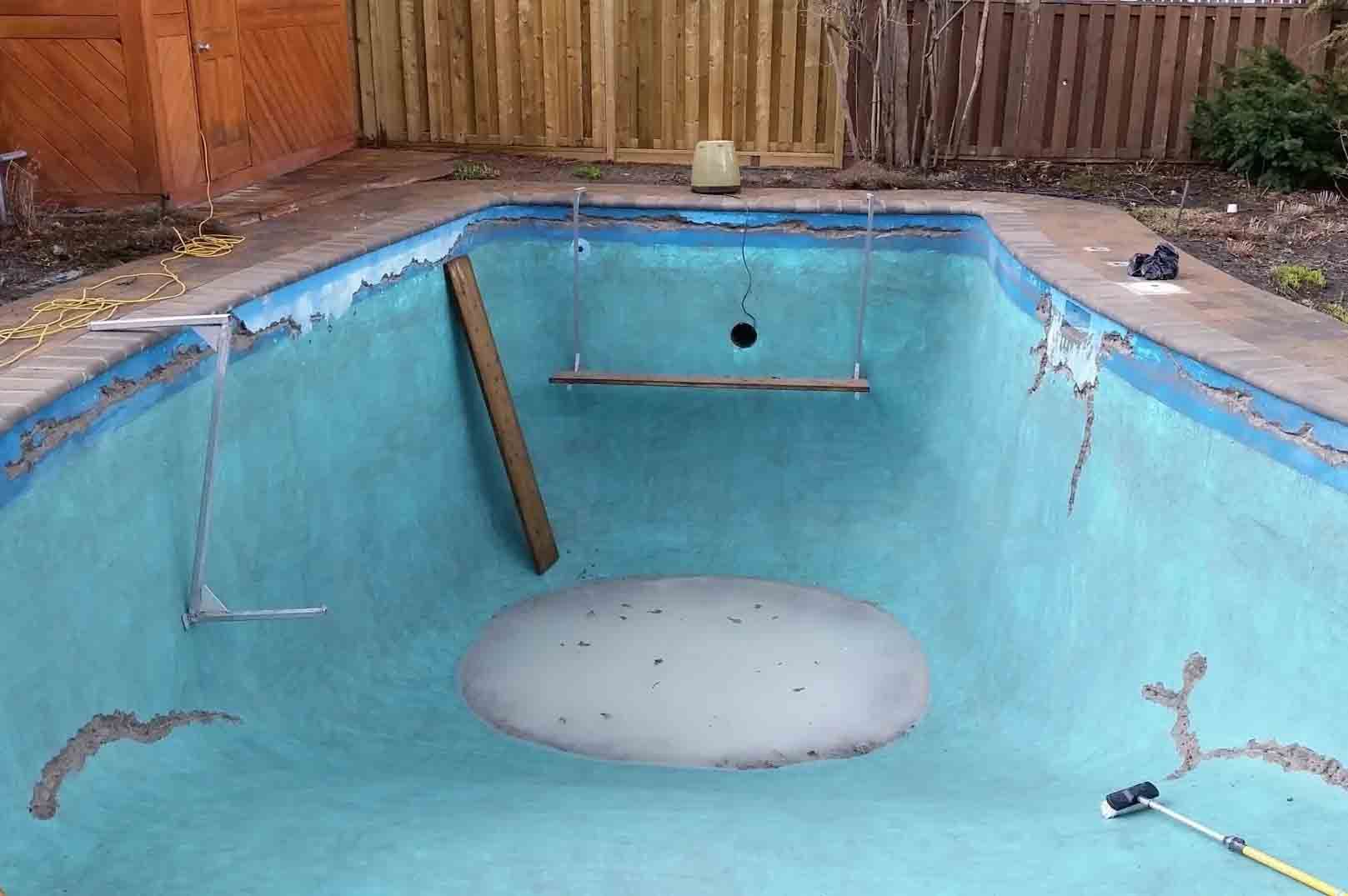 Piscine vide en cours de r&eacute;novation avec enduit de base et &eacute;l&eacute;ments de r&eacute;paration